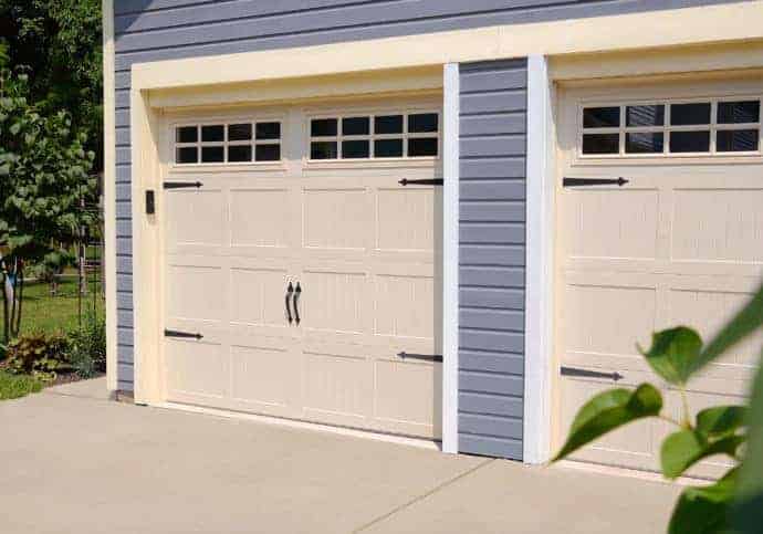Almond coach house garage door with decorative hardware and paneling
