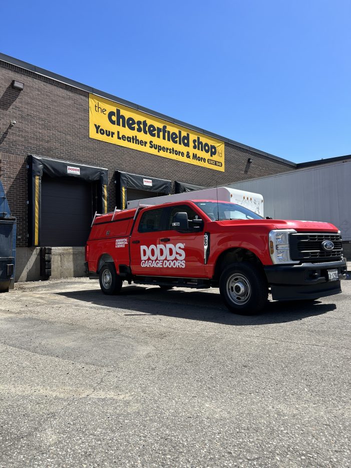 Red Dodds Garage Doors service truck parked outside a commercial garage door installation site.