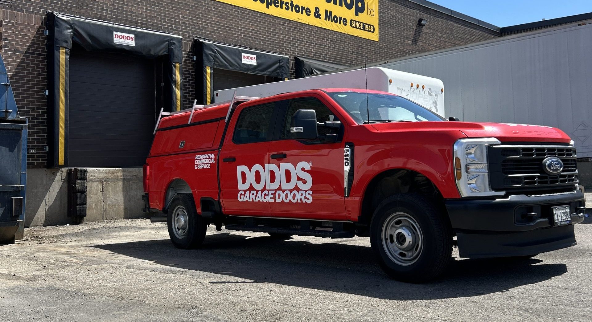 Red Dodds Garage Doors service truck parked outside a commercial garage door installation site.