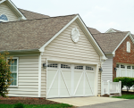 Classic white crossbuck garage door with arched window inserts on a suburban home.