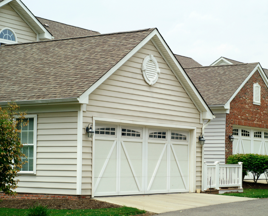 Classic white crossbuck garage door with arched window inserts on a suburban home.
