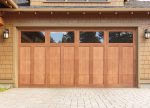 Contemporary natural wood grain garage door with rectangular glass window panels.