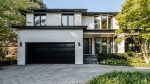 Minimalist black flush panel garage door on a contemporary luxury white stucco home.