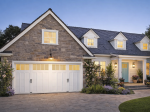 Traditional white carriage house garage door with top windows on a cottage-style stone house