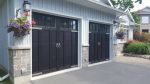 Traditional white carriage house garage door with top windows on a cottage-style stone house.