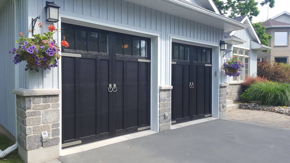 Traditional white carriage house garage door with top windows on a cottage-style stone house.