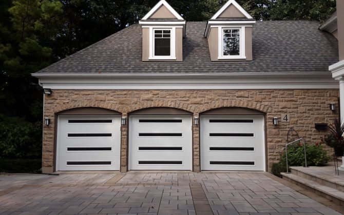 Three contemporary white garage doors with long horizontal frosted windows installed in Aurora, Ontario.