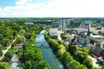 Aerial scenic view of the Speed River flowing through downtown Georgetown, Ontario, featuring local architecture and lush greenery.