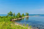 Blue water and green shoreline at the point of Couchiching Beach Park, a top Orillia waterfront destination.