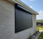 Durable black exterior security shutters on a brick home window, designed for residential theft prevention and sun control.