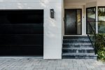 Matching black fiberglass entry door and modern garage door for a cohesive home exterior in Toronto.