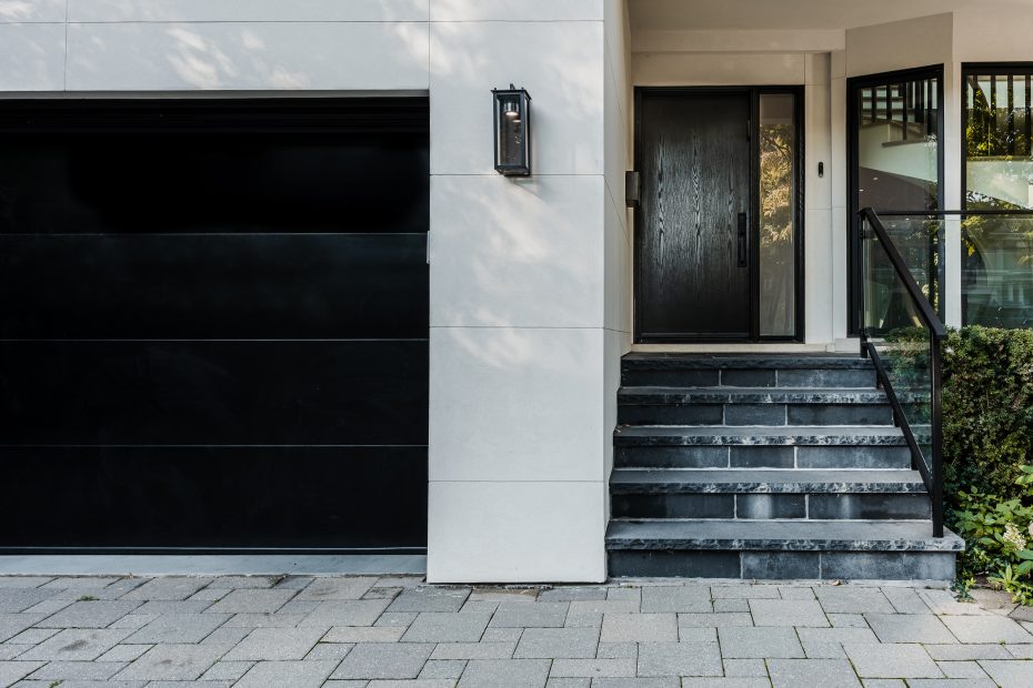 Matching black fiberglass entry door and modern garage door for a cohesive home exterior in Toronto.