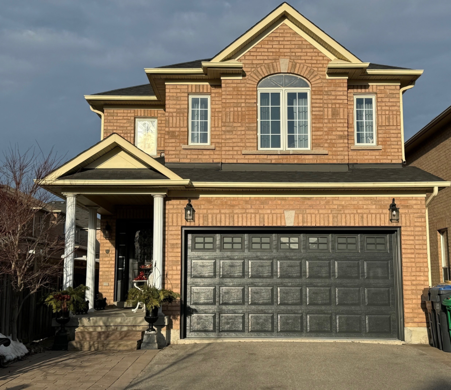 A newly installed black modern carriage-style garage door on a brick residential home in Georgetown, Ontario.