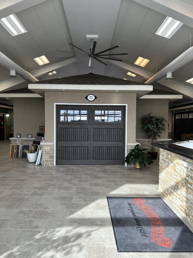 A dark wood-finish carriage house garage door on display inside the Dodds Doors Kingston showroom.