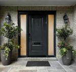 Charcoal gray fiberglass front door with frosted glass sidelights installed on a brick home entryway.
