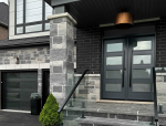 Modern charcoal grey double entry doors with horizontal glass inserts and long black pull handles matching a contemporary glass-panel garage door.