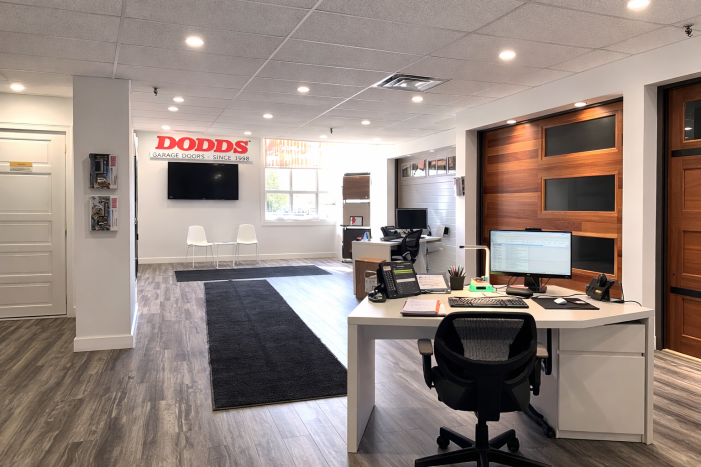 Dodds Garage Doors showroom interior featuring a modern wood plank garage door with frosted glass windows and office consultation area.