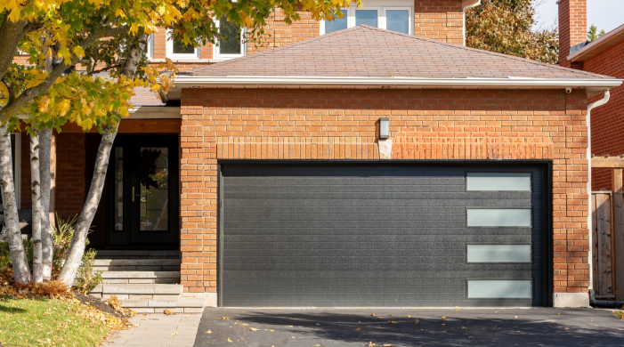 Modern black garage door from the Dodds Platinum Series featuring a sleek horizontal plank design and side-stacked frosted glass windows on a red brick house.