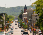 Busy downtown Milton Ontario Main Street featuring historic stone buildings, local shops, and the Niagara Escarpment in the background