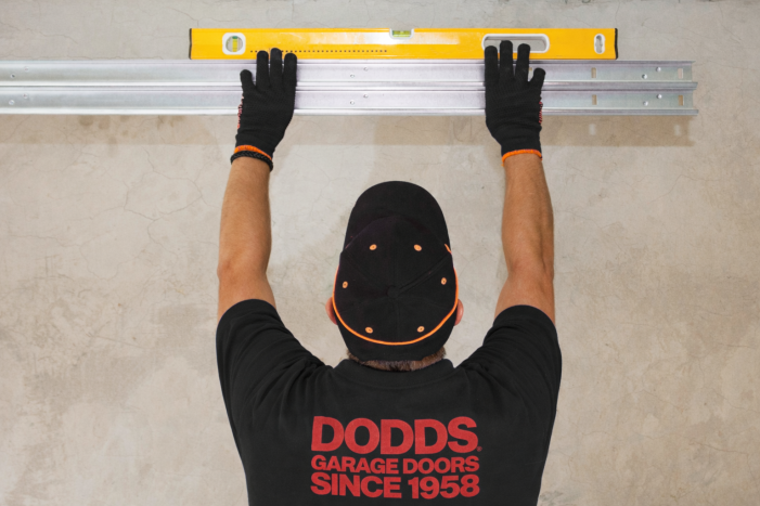 A Dodds Garage Doors technician using a level to ensure a precise overhead door track installation in Aurora.
