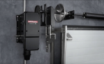 A wall-mounted commercial jackshaft garage door opener connected directly to the torsion shaft and springs of a sectional industrial door.