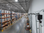 Industrial garage door with high-lift tracks equipped with a side-mount electronic jackshaft opener to maximize overhead warehouse space.