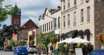 The historic Thompson House building in Milton Ontario with outdoor patio seating and a blue car driving by local storefronts