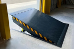 Close-up view of a steel hydraulic dock leveler lip and bumper pads, showing the durable construction for commercial loading docks.