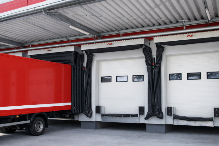 Air-inflated dock seals expanding around a delivery trailer to provide a superior customizable barrier against moisture and debris at a logistics hub.
