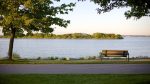 A quiet park bench facing Lake Couchiching at Couchiching Beach Park in Orillia, Ontario.