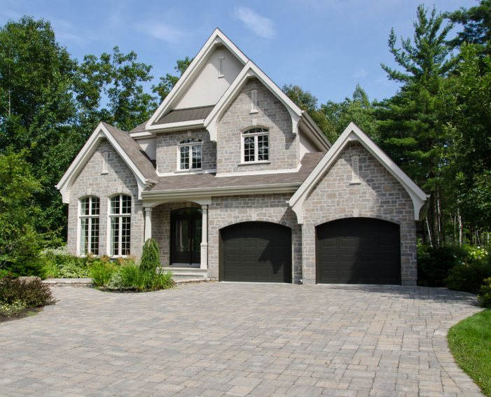 Custom dark-paneled double garage doors installed on a luxury stone home in Burlington.