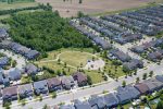 "High-angle drone shot of a Milton Ontario community park with a children's playground, walking paths, and surrounding detached suburban houses.