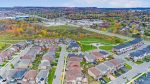 Aerial view of a modern Milton Ontario residential neighborhood with family homes, green space, and colorful autumn trees near the Niagara Escarpment.