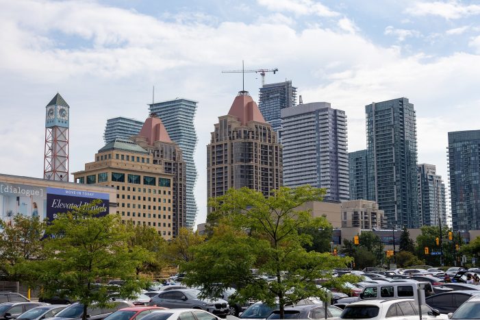 Urban view of Mississauga City Centre buildings, clock tower, and residential high-rises from a local parking lot.
