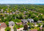 Aerial drone view of a lush, green residential neighborhood in Mississauga with a view of the Toronto skyline in the distance.