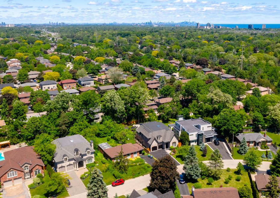 Aerial drone view of a lush, green residential neighborhood in Mississauga with a view of the Toronto skyline in the distance.
