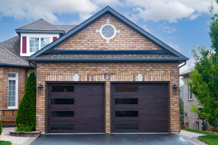 A newly installed modern garage door with windows on a brick home in Oshawa.