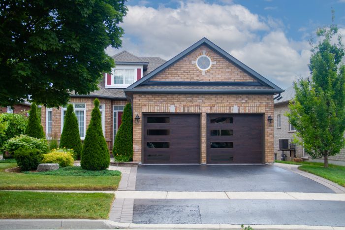 Residential garage door replacement in Cambridge featuring charcoal steel doors with decorative glass window inserts.