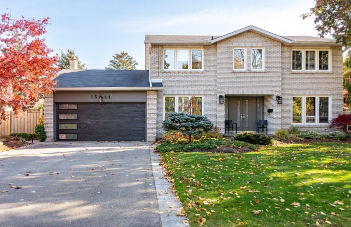 Modern grey garage door with vertical windows installed on a brick home in Kitchener.