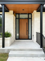Vertical oak wood entry door with a long black pull bar handle and frosted glass sidelites.