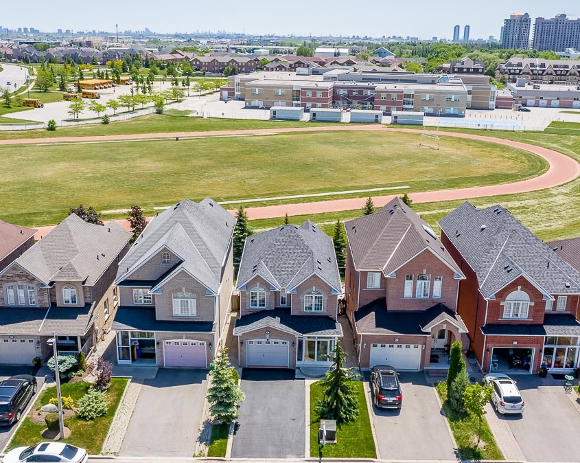 Modern suburban homes in Maple, ON, adjacent to a local school, showing various garage door styles available for installation.