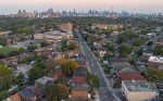 Elevated view of a Toronto residential street with a skyline backdrop at sunset.