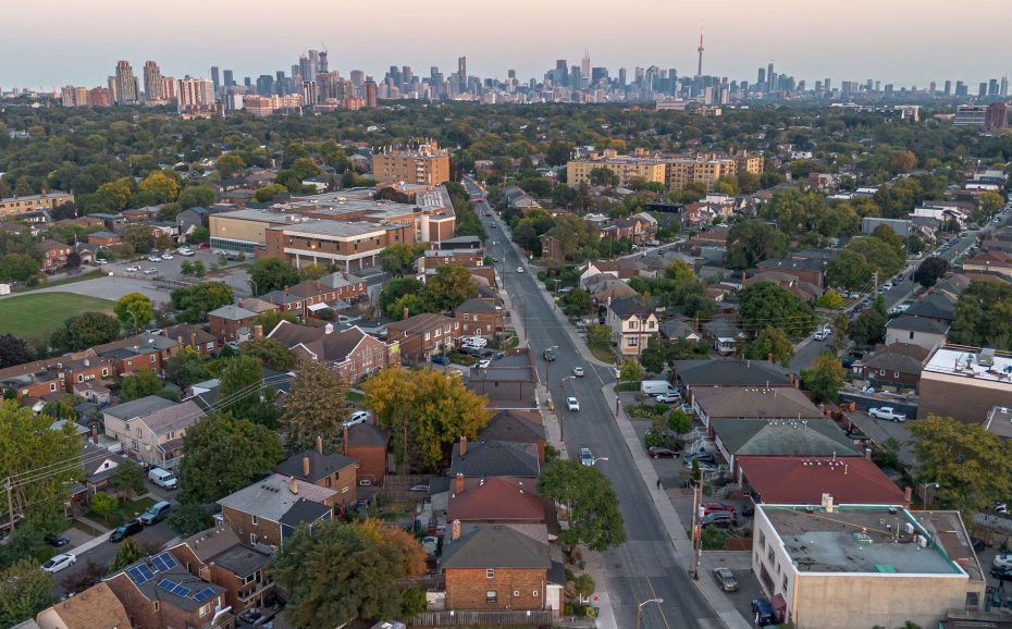 Elevated view of a Toronto residential street with a skyline backdrop at sunset.