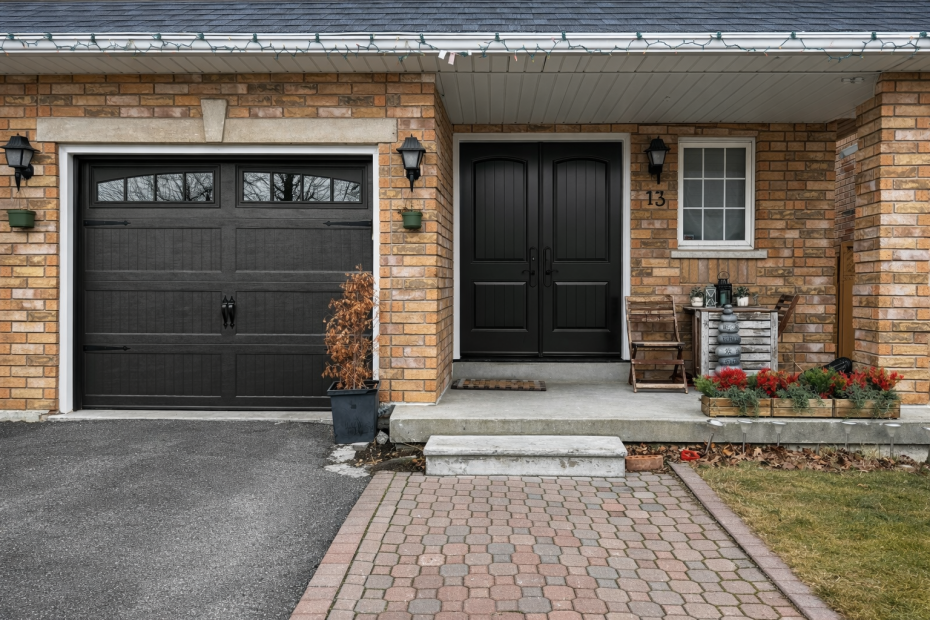 Traditional black double entry doors with arched panels paired with a matching black carriage-style garage door on a brick home for improved curb appeal.