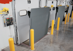 Multiple vertical storing dock levelers in the upright position, allowing for easy floor cleaning and overhead door closure in a clean warehouse environment.