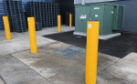 High-visibility yellow industrial safety bollards protecting electrical equipment in a warehouse loading area.