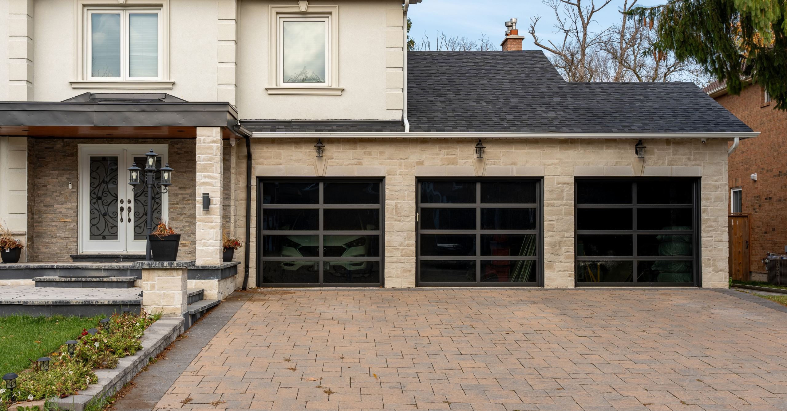 Close-up of residential black aluminum frame garage doors with tinted glass panels.