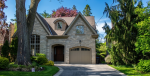Full exterior view of a luxury stone house featuring a custom garage door installed by Dodds Garage Doors with a paved driveway.