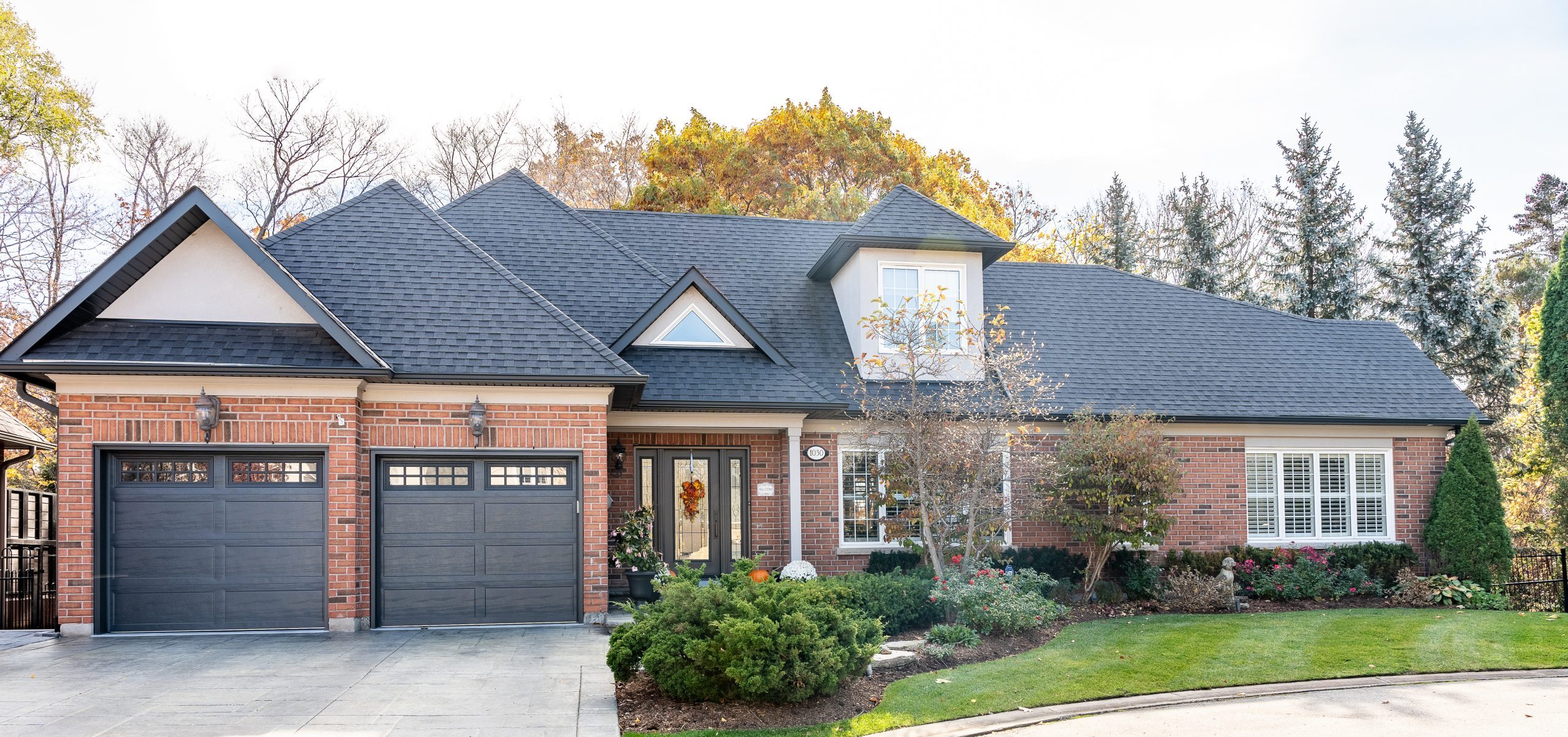 Dodds modern residential garage doors featuring a premium dark woodgrain finish selected by the homeowner, complete with vertical-stacked side windows.