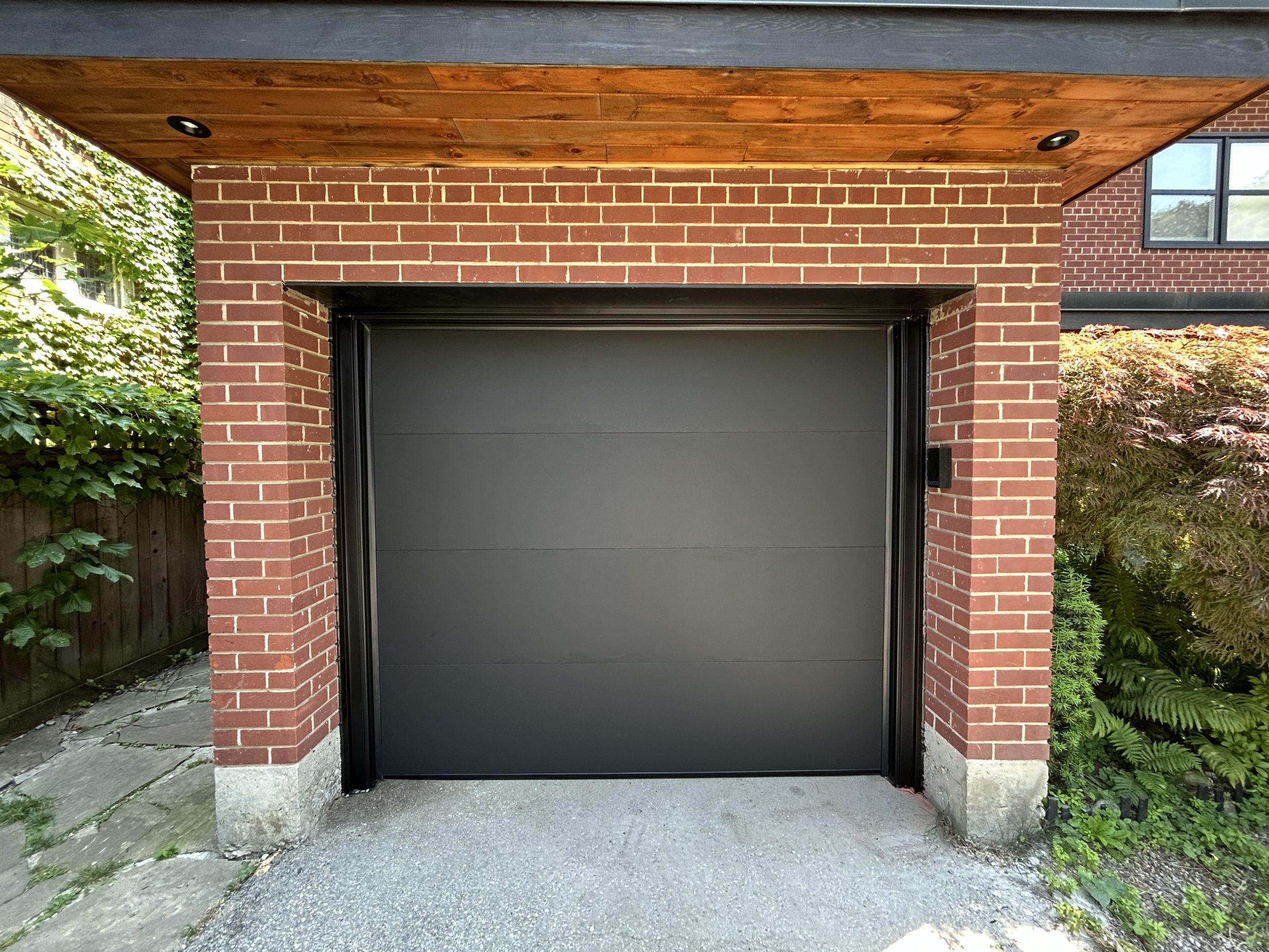 Completed modern garage door installation in Toronto featuring a Dodds ultra flush black contemporary door.